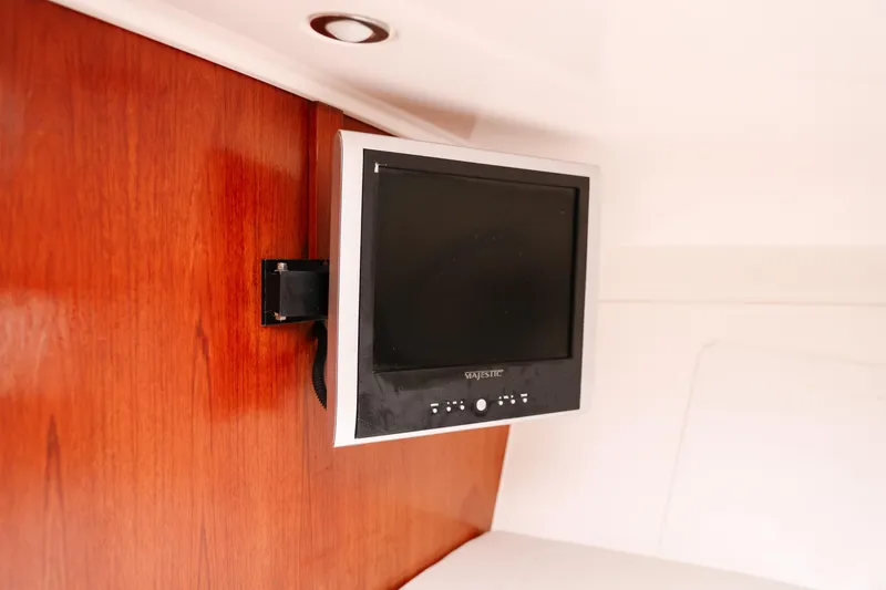 Slide: The Image of Wall-mounted TV inside 2010 Everglades 350LX boat cabin with wooden paneling. - 31