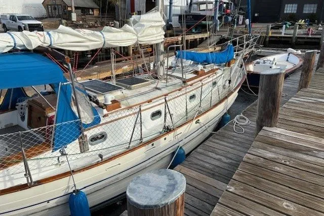Slide: The Image of 1986 Tayana 37 sailboat docked at a marina, featuring classic design and blue accents. - 13