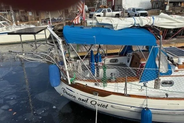 Slide: The Image of 1986 Tayana 37 sailboat named "Peace and Quiet" docked with blue canopy and fenders. - 14