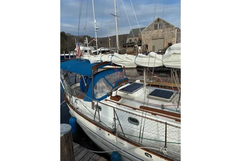Slide: The Image of 1986 Tayana 37 sailboat docked, featuring blue canopy and solar panels. - 15