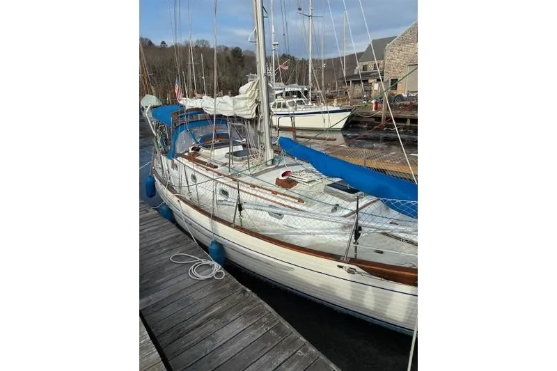 Slide: The Image of 1986 Tayana 37 sailboat docked, featuring blue canvas and wooden accents. - 16