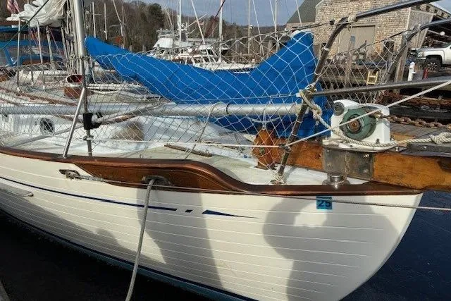 Slide: The Image of 1986 Tayana 37 sailboat docked, featuring wooden trim and blue sail cover. - 2