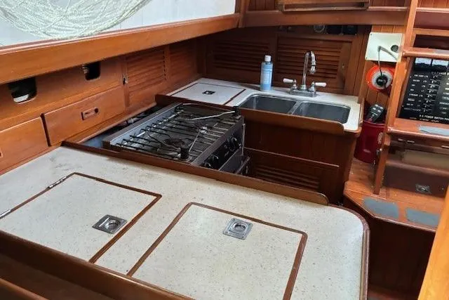 Slide: The Image of 1986 Tayana 37 yacht kitchen with stove, sink, and wooden cabinetry. - 28