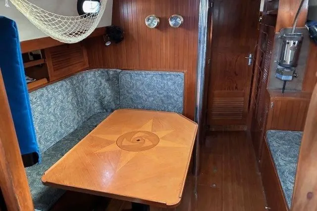 Slide: The Image of Cozy interior of 1986 Tayana 37 sailboat with wooden table and cushioned seating. - 3