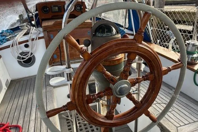 Slide: The Image of 1986 Tayana 37 sailboat cockpit with wooden steering wheel and nautical equipment. - 8