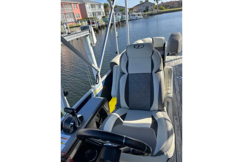 Slide: The Image of 2022 Veranda VP 25RC boat interior with luxurious seating and steering wheel, dockside view. - 12