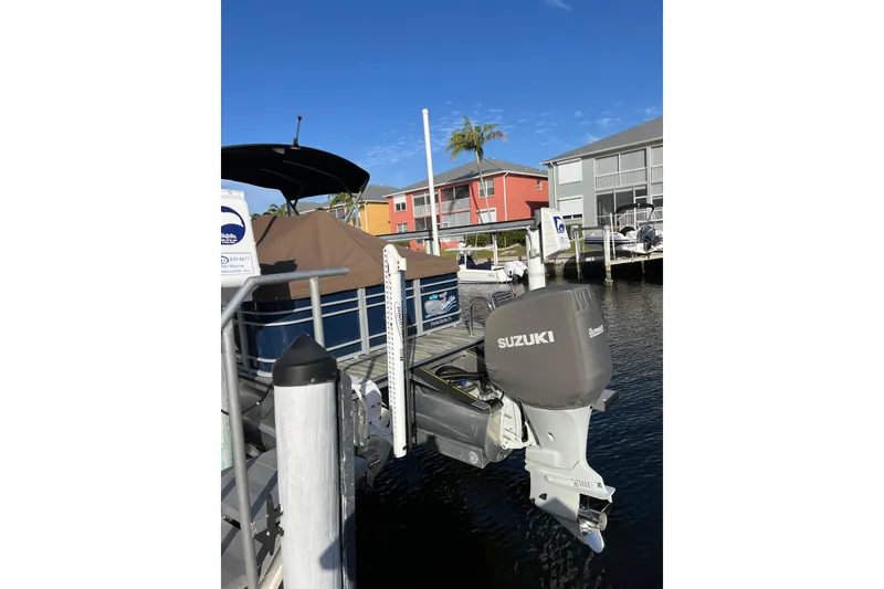 Slide: The Image of 2022 Veranda VP 25RC pontoon boat docked with Suzuki outboard motor. - 2