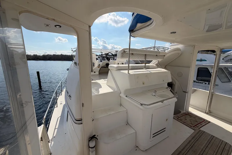 Slide: The Image of 1997 Sea Ray 370 Aft Cabin yacht interior with helm and seating area, docked by the water. - 25