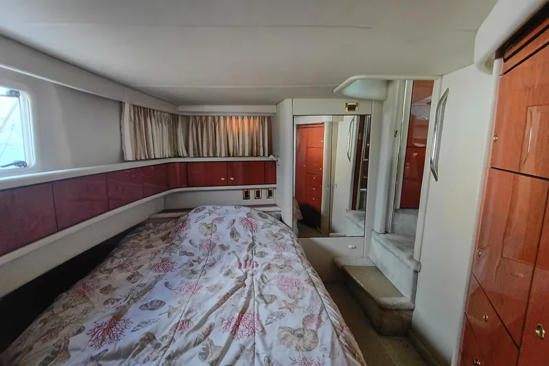 Slide: The Image of 1997 Sea Ray 370 Aft Cabin interior with bed, wooden cabinets, and mirrored closet. - 70