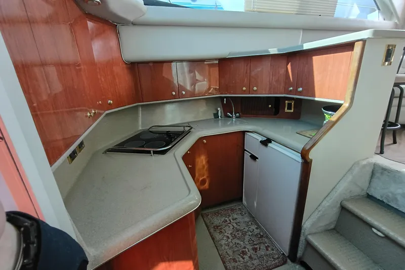 Slide: The Image of 1997 Sea Ray 370 Aft Cabin kitchen with wood cabinets and compact appliances. - 75