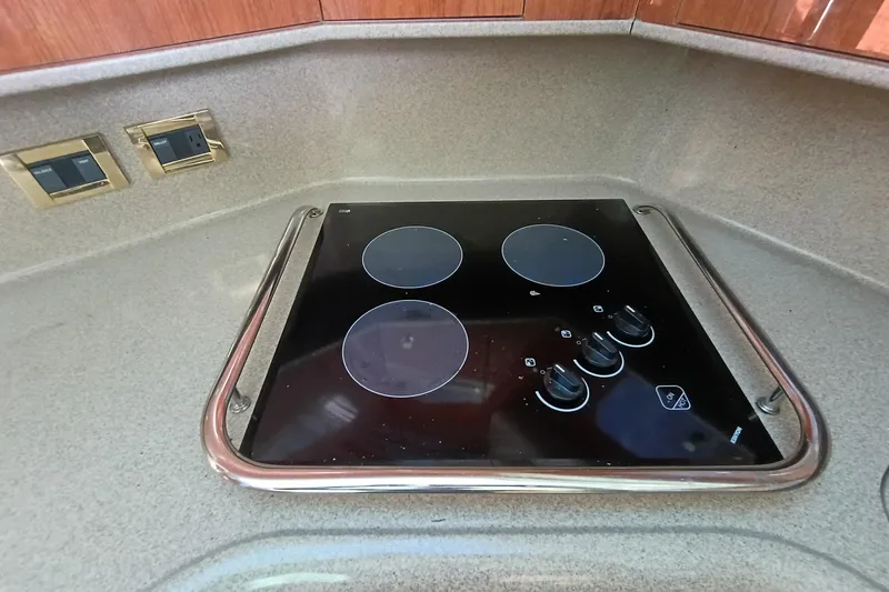 Slide: The Image of 1997 Sea Ray 370 Aft Cabin kitchen with electric stovetop and sleek countertop design. - 79