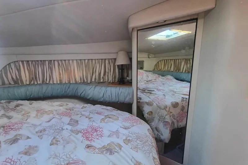 Slide: The Image of 1997 Sea Ray 370 Aft Cabin bedroom with seashell-patterned bedding and mirrored closet. - 89
