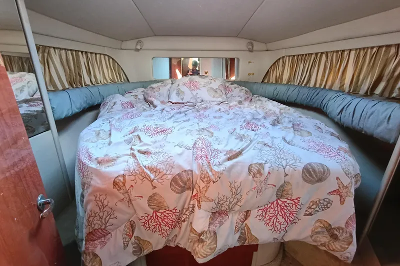 Slide: The Image of 1997 Sea Ray 370 Aft Cabin bedroom with seashell-themed bedding and cozy interior. - 90