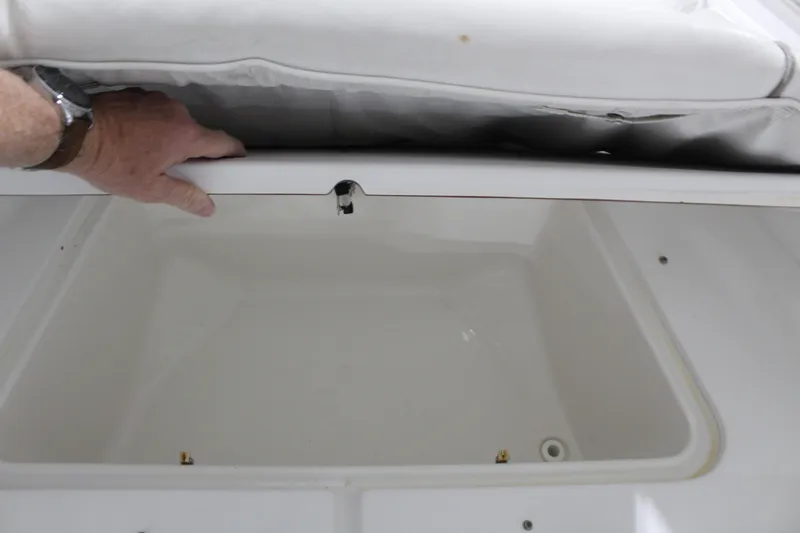 Slide: The Image of 2012 Sea Hunt Edge 24 storage compartment with cushioned lid being opened. - 28