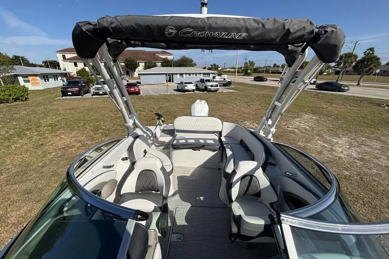 Slide: The Image of 2026 Crownline Eclipse E260 XS boat interior with seating and canopy, parked on grass. - 12