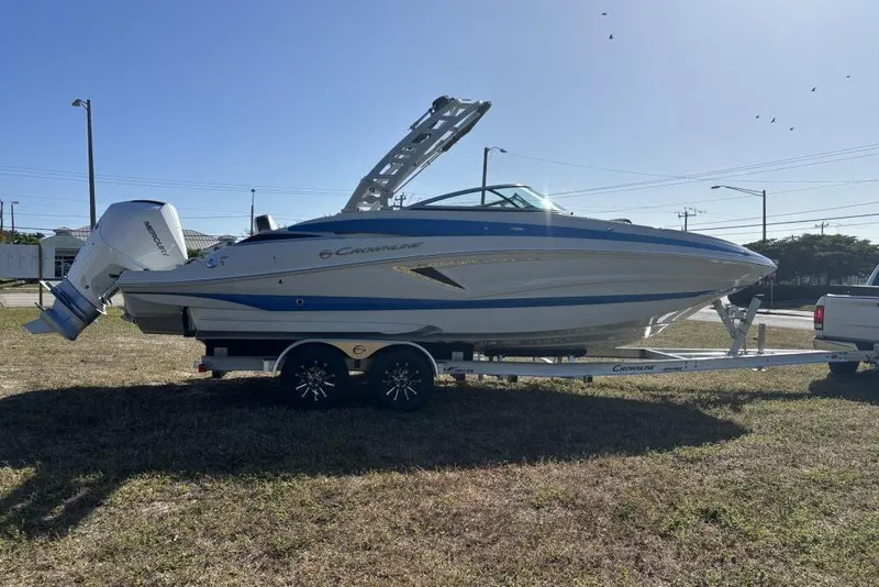 Slide: The Image of 2026 Crownline Eclipse E260 XS boat on trailer, parked outdoors under clear sky. - 2