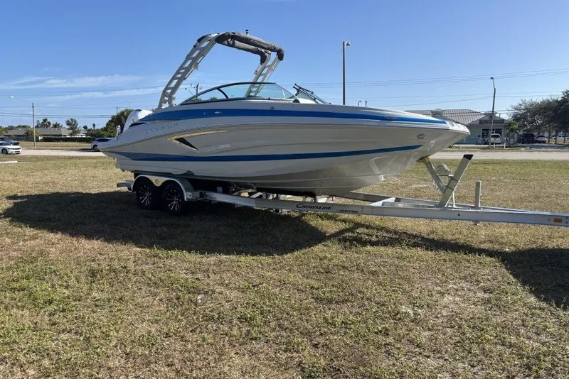 Slide: The Image of 2026 Crownline Eclipse E260 XS boat on trailer, parked on grass under clear sky. - 8