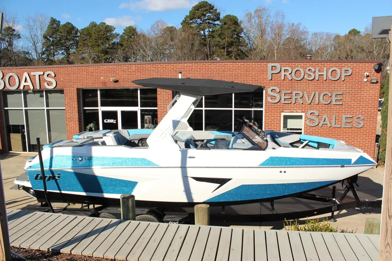 Slide: The Image of 2026 Tigé 24RZX boat displayed outside a pro shop, featuring sleek design and blue accents. - 2