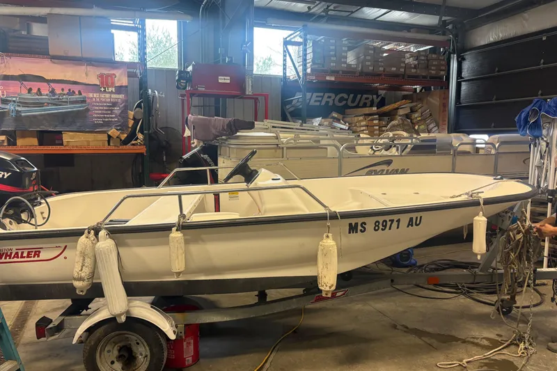 The Image of 2001 Boston Whaler 130 Super Sport boat in a garage with equipment and accessories. - 1