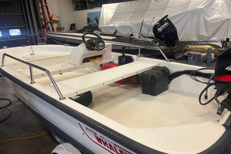 Slide: The Image of 2001 Boston Whaler 130 Super Sport boat in a garage with Suzuki outboard motor. - 5