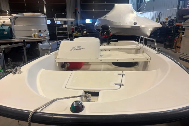 Slide: The Image of 2001 Boston Whaler 130 Super Sport boat in a garage, showcasing interior and motor. - 6