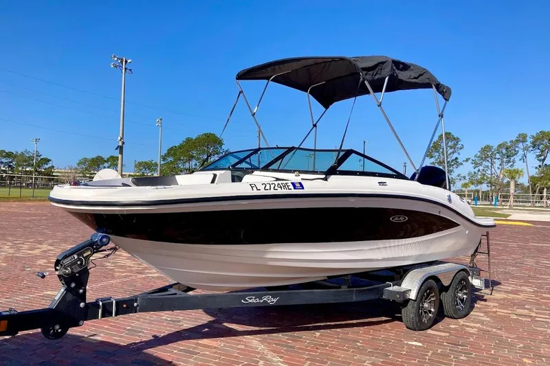 Slide: The Image of 2017 Sea Ray 19 SPX OB boat on trailer, parked on brick pavement under clear blue sky. - 1