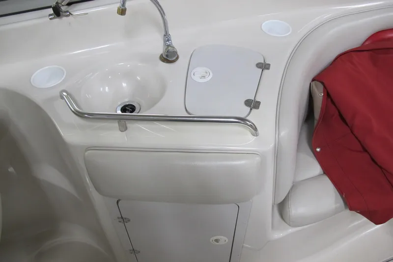Slide: The Image of 2003 Crownline 270 BR boat interior with sink and red cover. - 10