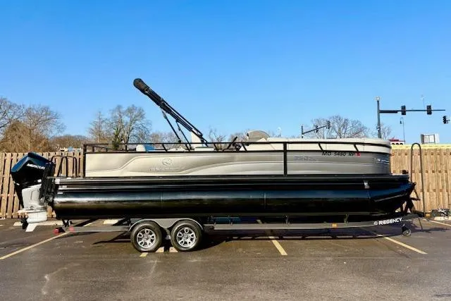 Slide: The Image of 2025 Regency 250 DL3 pontoon boat on trailer in parking lot, clear blue sky. - 36