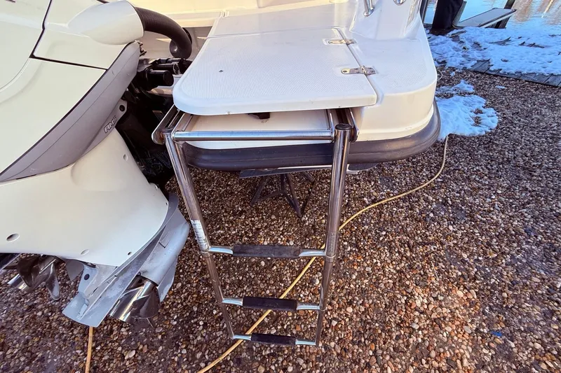 Slide: The Image of 2017 Boston Whaler 320 Vantage boat with a retractable swim ladder on gravel. - 10