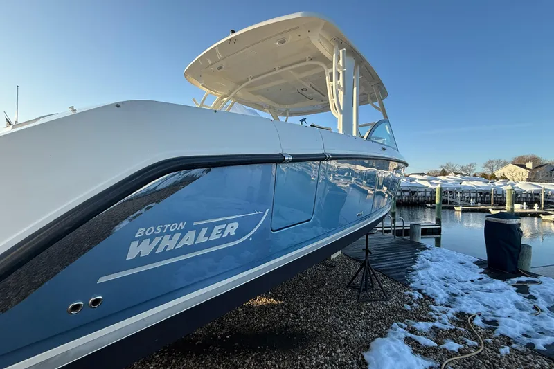 Slide: The Image of 2017 Boston Whaler 320 Vantage boat docked, showcasing sleek design and blue hull. - 2