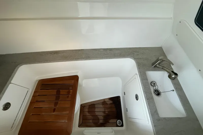 Slide: The Image of 2017 Boston Whaler 320 Vantage boat sink area with wooden covers and faucet. - 52