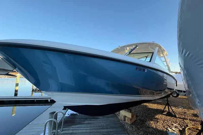 Slide: The Image of 2017 Boston Whaler 320 Vantage boat docked, showcasing sleek blue hull design. - 62