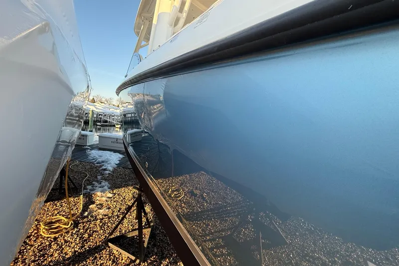 Slide: The Image of 2017 Boston Whaler 320 Vantage boat hull, blue finish, docked on gravel. - 7