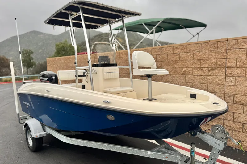 Slide: The Image of 2017 Bayliner Element F18 boat on trailer, parked outdoors with mountains in background. - 1