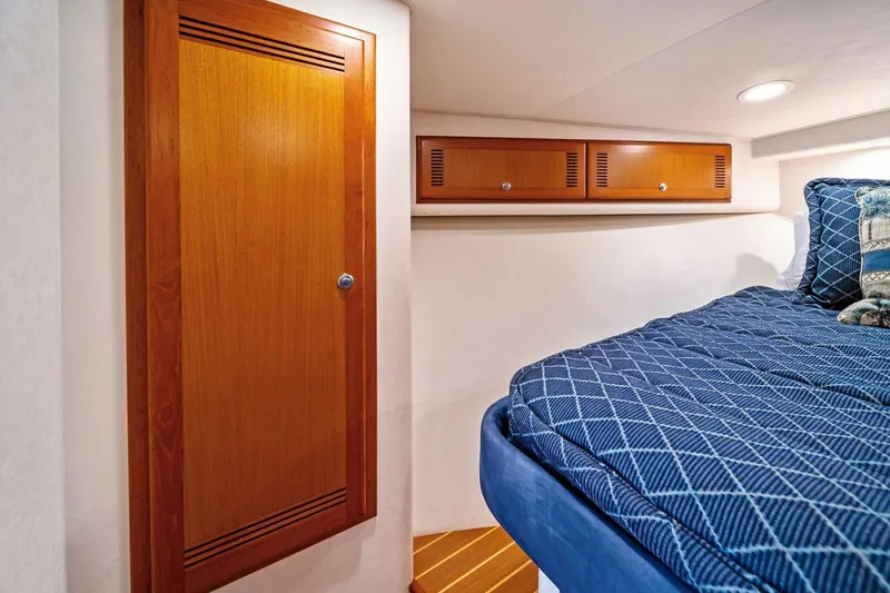 Slide: The Image of Interior cabin of 2005 Cabo 40 Express yacht with wooden cabinetry and blue bedding. - 40