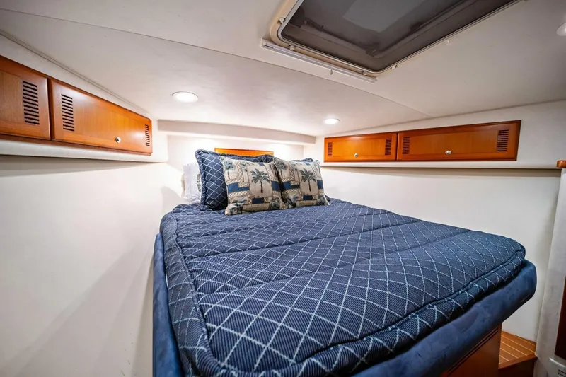 Slide: The Image of 2005 Cabo 40 Express cabin with cozy bed, blue bedding, and wooden storage cabinets. - 42