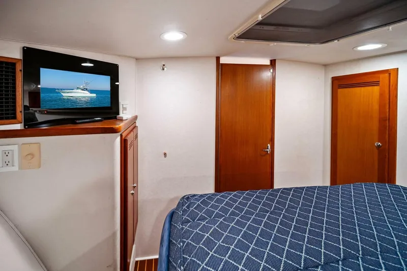 Slide: The Image of 2005 Cabo 40 Express cabin interior with TV, wooden doors, and patterned bedding. - 44