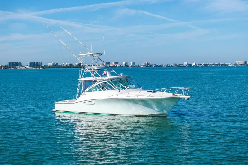 Slide: The Image of 2005 Cabo 40 Express yacht on calm blue waters with city skyline in background. - 64