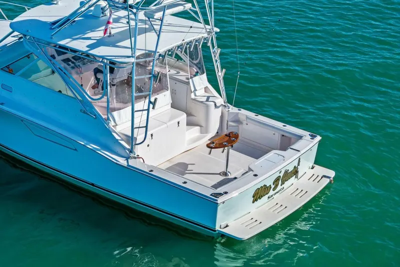 Slide: The Image of 2005 Cabo 40 Express boat on clear blue water, featuring a spacious deck. - 67
