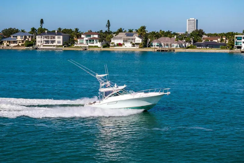 Slide: The Image of 2005 Cabo 40 Express yacht cruising on blue water near waterfront homes. - 75