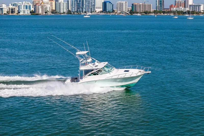 Slide: The Image of 2005 Cabo 40 Express yacht cruising on blue water with city skyline backdrop. - 76