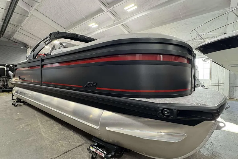 Slide: The Image of 2026 Viaggio x22u pontoon boat in a warehouse, sleek black and red design. - 3