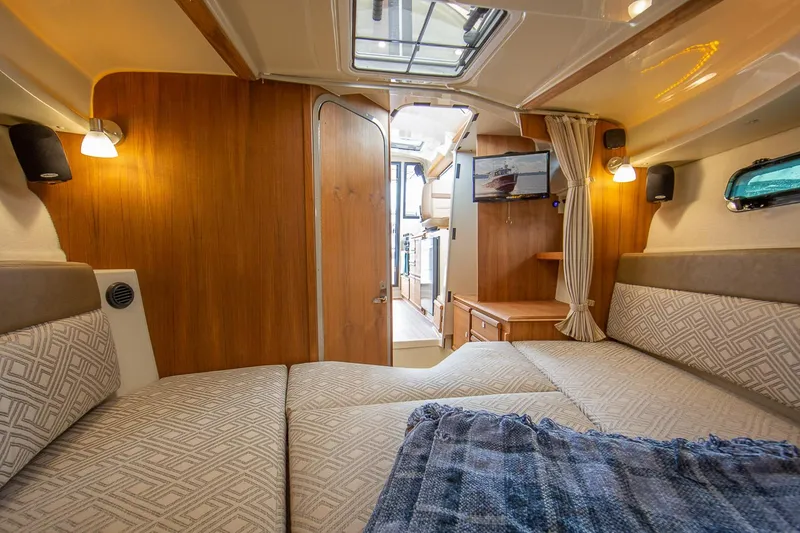 Slide: The Image of Manufacturer Provided Image: Interior of 2025 Ranger Tugs R-27 boat, featuring cozy cabin with bed and wooden accents. - 20