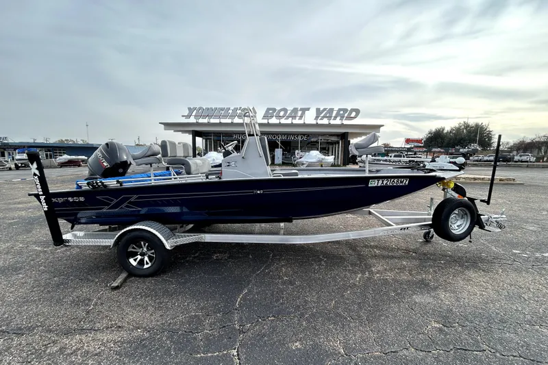 The Image of 2025 Xpress H20B Bay boat on trailer at dealership, overcast sky. - 0