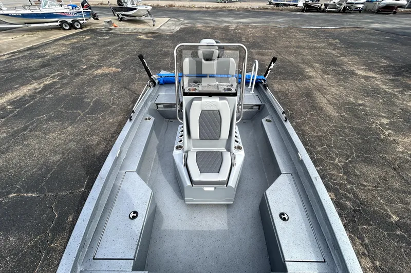 Slide: The Image of 2025 Xpress H20B Bay boat interior with seating and console, parked on asphalt. - 22