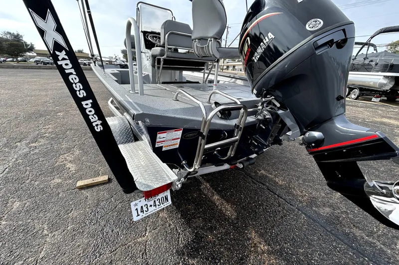 Slide: The Image of 2025 Xpress H20B Bay boat with Yamaha outboard motor and ladder, parked on asphalt. - 6