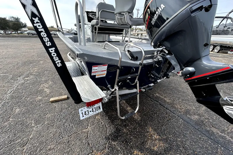 Slide: The Image of 2025 Xpress H20B Bay boat with Yamaha motor and ladder, parked on asphalt. - 7