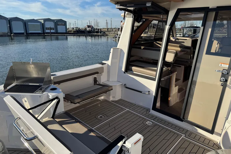 Slide: The Image of 2025 Cutwater C-288 Coupe boat interior with seating and grill, docked by the water. - 10