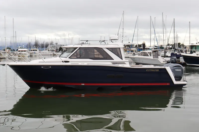 Slide: The Image of 2025 Cutwater C-288 Coupe boat docked in a marina, side view. - 2