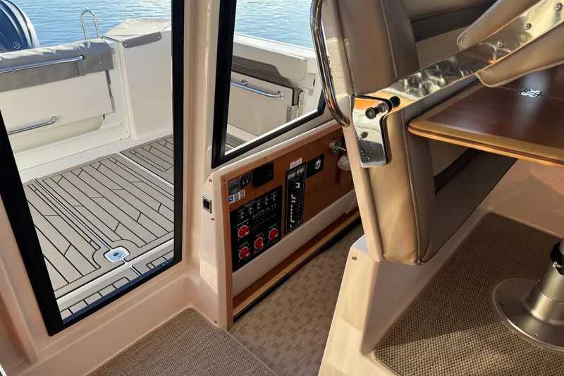 Slide: The Image of 2025 Cutwater C-288 Coupe interior, featuring control panel and seating area with wooden table. - 21